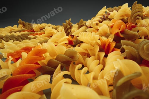 Preview: Uncooked pasta swirls on dark background macro