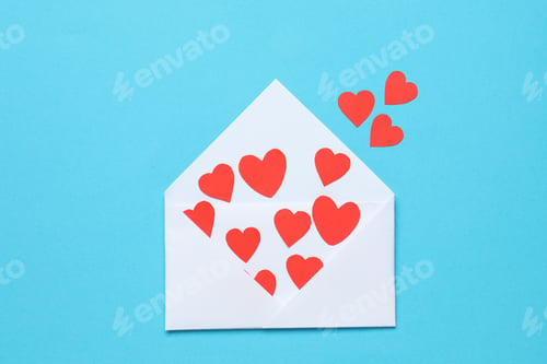 Preview: Valentine's Day. Envelope with many paper hearts on light blue background, top view