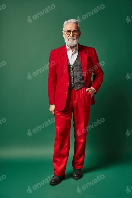 Preview: classy man dressed as Santa posing with one hand in pocket on green backdrop, winter concept