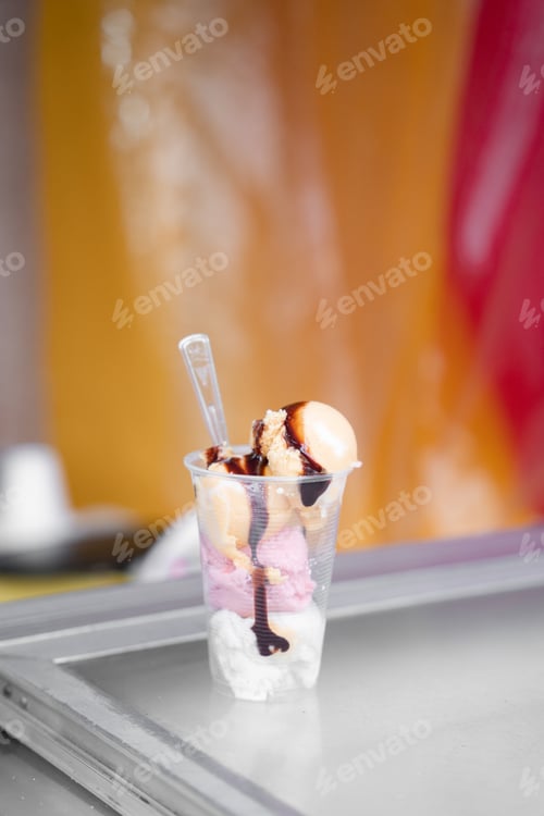 Preview: A four ball ice cream served in a plastic cup with a spoon in a street market stall