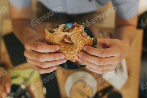 Preview: Man holding in hands a half eaten sandwich