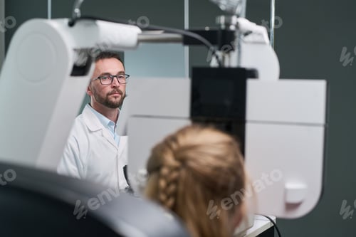 Preview: Male Optometrist Examining Young Patient with Device