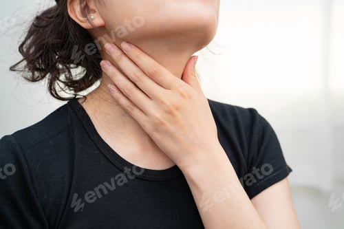 Preview: Asian woman touching her neck and throat for thyroid gland problem.