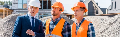 Preview: constructors in helmets standing near businessman in suit and houses