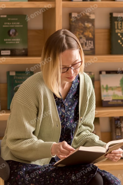 Preview: young woman sitting with a book in the library