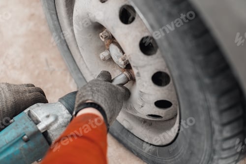 Preview: Mechanic repairing broken car or seasonal wheel concept. Close-up of male hands using electric tool