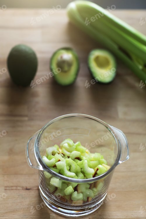 Preview: Glass jar with raw chopped celery, avocado and apple, ingridients for health green organic smoothie.