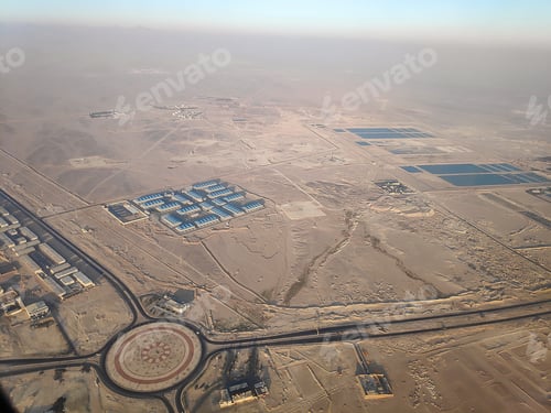 Preview: Aerial view from airplane window,porthole of city buildings, water reservoir at sandy desert at day