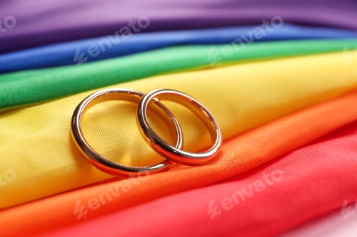 Preview: Wedding rings on rainbow LGBT flag, closeup