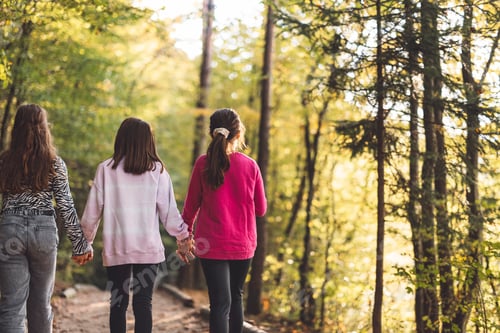 Preview: Three young girls smiling and posing on a wooden bridge in a forest. They are holding colorful lolli