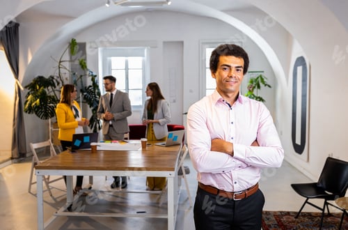 Preview: Portrait of smiling African American businessman in office with his colleagues in background.