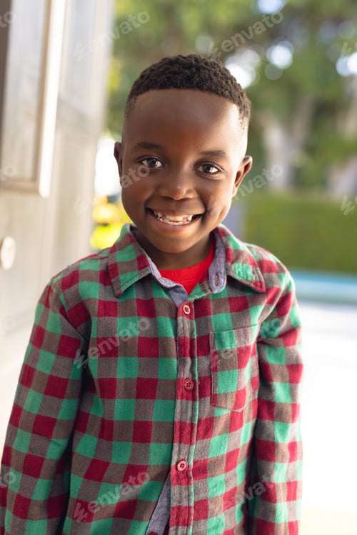 Preview: Vertical picture of happy african american boy welcoming somebody outside the house