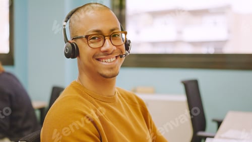 Homem sorridente usando fone de ouvido enquanto trabalha em um coworking