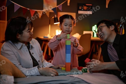 Preview: Asian Parents Watching Young Daughter Building Tower with Colorful Blocks