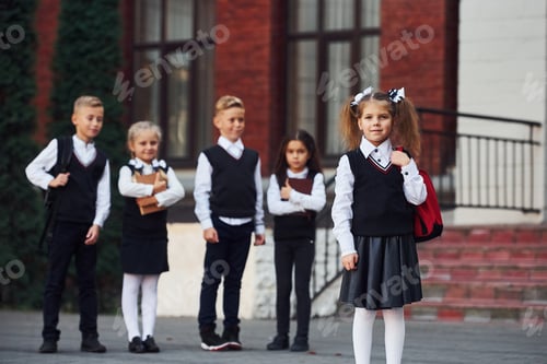 Preview: Group of kids in school uniform posing to the camera outdoors together near education building
