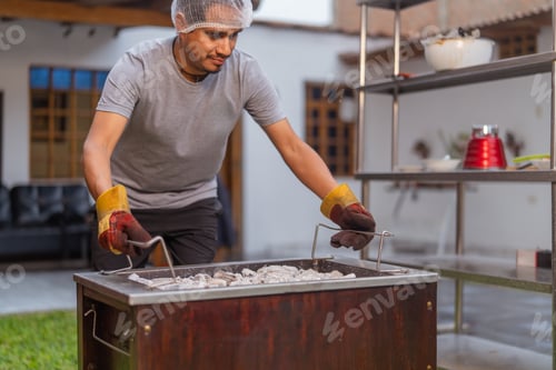 Preview: Chef heating charcoal in barbecue grill getting ready for cooking outdoors