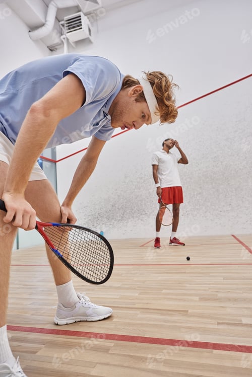 Preview: tired multicultural players in sportswear breathing heavily after playing squash in court