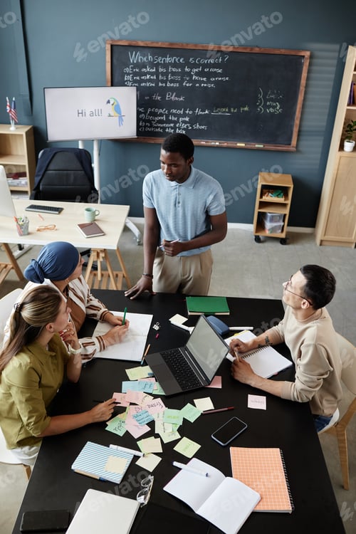 Preview: Male English Teacher Talking to Students Sitting at Desk during Speaking Club Meeting