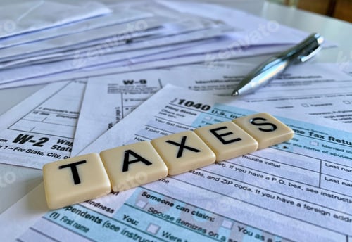 Preview: Low angle of letter tiles with the word TAXES on a variety of tax forms.