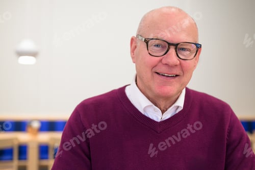 Preview: Portrait of a smiling senior man with eyeglasses in an office