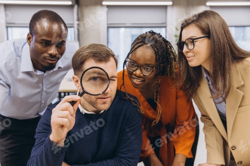 Preview: Diverse business team examining financial data through magnifying glass, collaborating