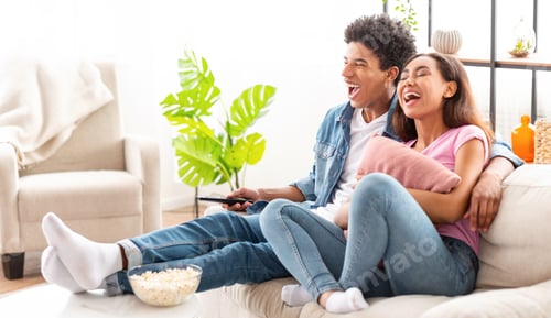Preview: Couple Laughing While Watching Television Together On The Couch