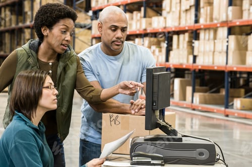 Preview: Warehouse workers checking inventory on a computer in a large distrubiton warehouse.