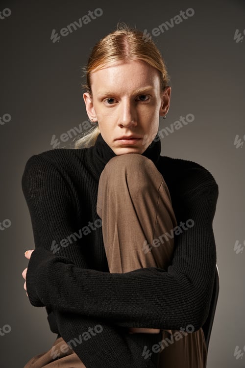 Preview: young attractive non binary person with ponytail and black turtleneck posing and looking at camera