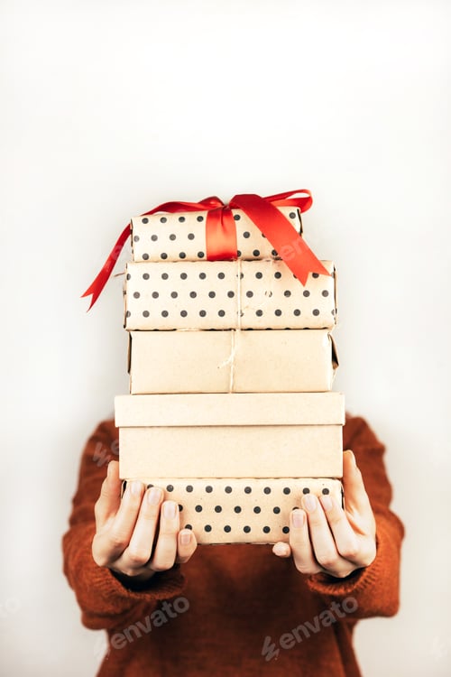 Preview: Closeup stack of boxes in female hands. A face of person is not visible. Vertical image