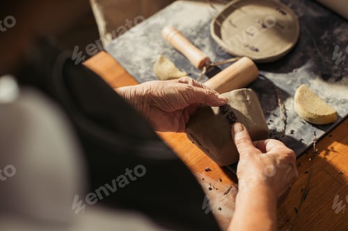 Preview: Potter decorating clay vase with lavender flowers in workshop