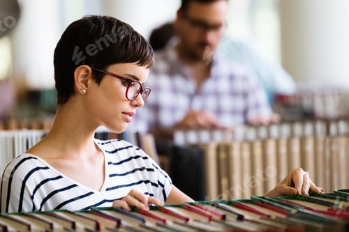 Preview: Portrait of a pretty smiling girl reading book in library
