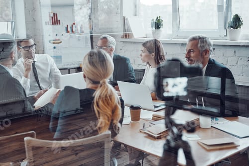 Preview: Successful business team discussing strategy while filming staff meeting in the board room
