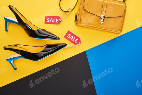 Preview: Top View of Shoes And Bag With Sale Label on Blue, Yellow And Black Background
