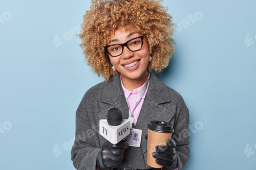 Preview: Positive female journalist prepares broadcasting holds microphone and takeaway coffee gets ready for