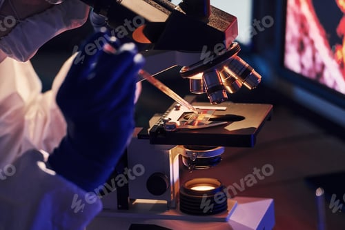 Preview: Scientist in white protective uniform works with coronavirus and blood tubes in laboratory