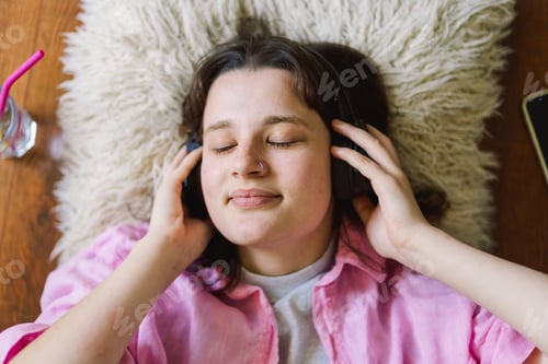 Preview: Teengirl Relaxing on the Floor With Headphones and a Drink