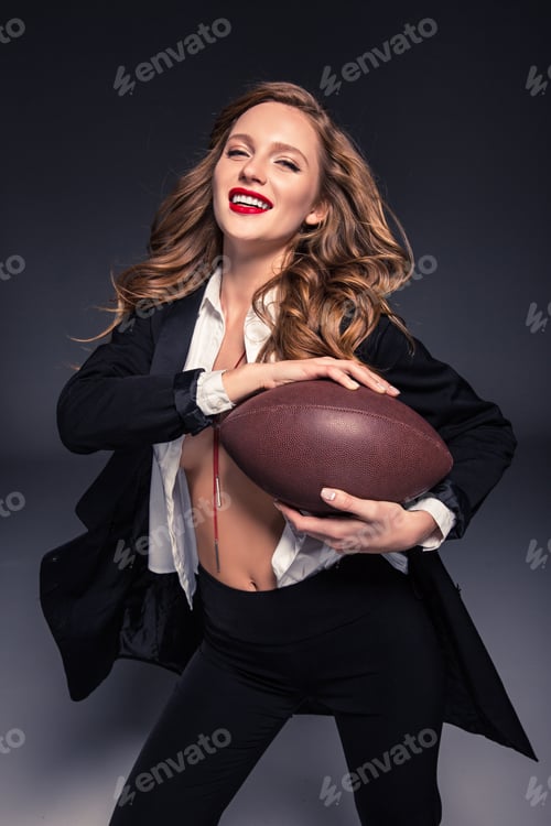Preview: happy woman with curly hair holding american football ball