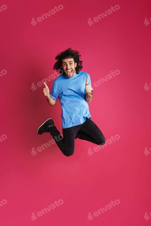 Preview: Excited brunette man jumping and showing thumb up