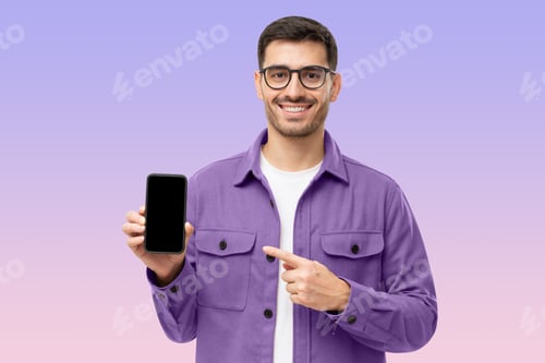 Preview: Handsome man in purple shirt presenting smart phone and pointing with finger at blank black screen