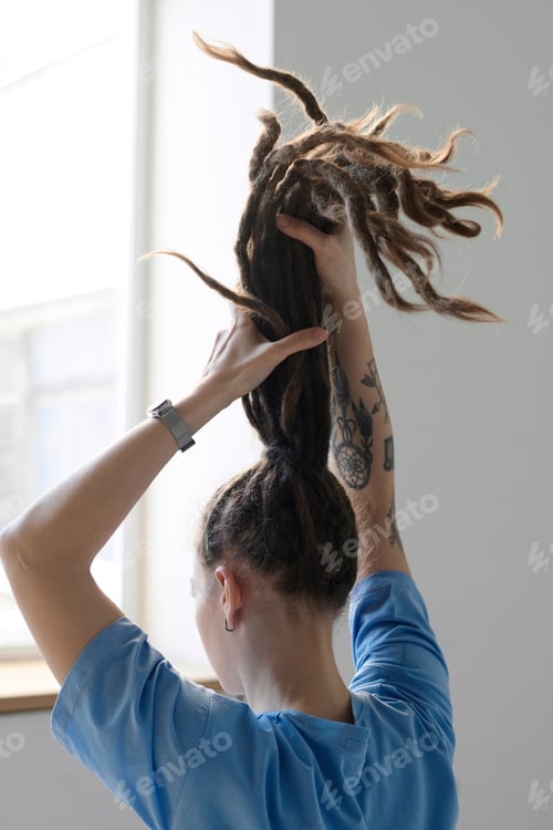 Preview: Back View of Woman Holding Long Dreadlocks in Ponytail