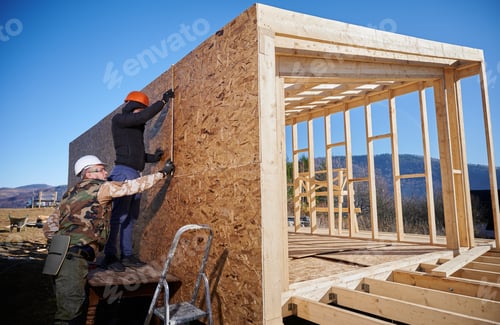 Preview: Carpenter hammering nail into OSB panel while building wooden frame house.