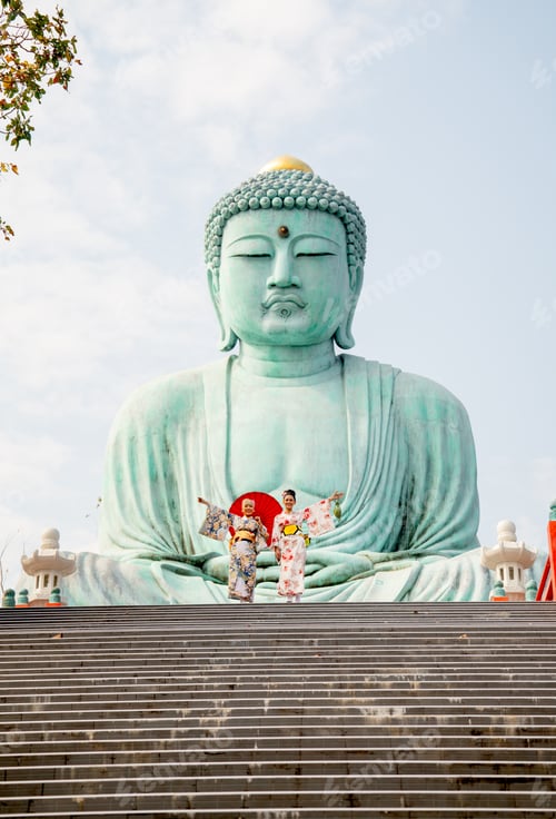 Preview: Two Asian young woman with japanese style dress stay on base of green big buddha statue
