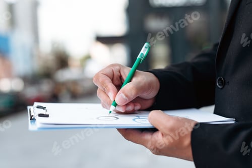 Preview: Business concept. Male hand with a pen makes notes outdoors
