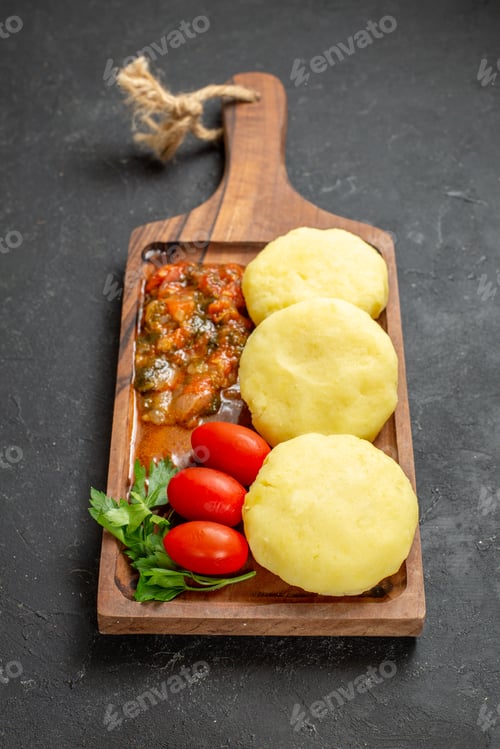 Preview: Vertical view of uncooked vegetables on a brown cutting board on the black background