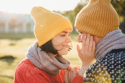 Preview: Female in warm hat, scarf and sweater, keeps hands on boyfriend`s cheek, have romantic moment.