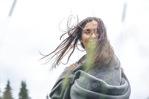 Preview: A young woman wrapped in a blanket in the mountains.