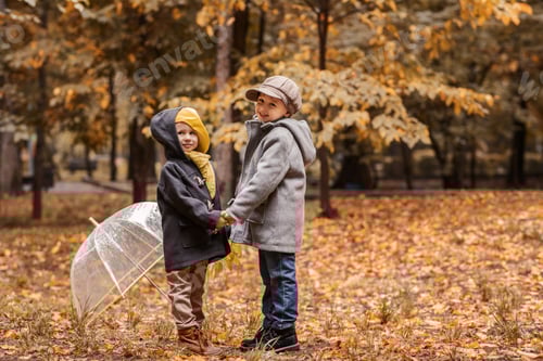 Preview: fun walk of attractive little girl and boy in the autumn park on a rainy day