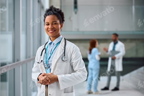 Preview: Happy black female doctor at medical clinic looking at camera.