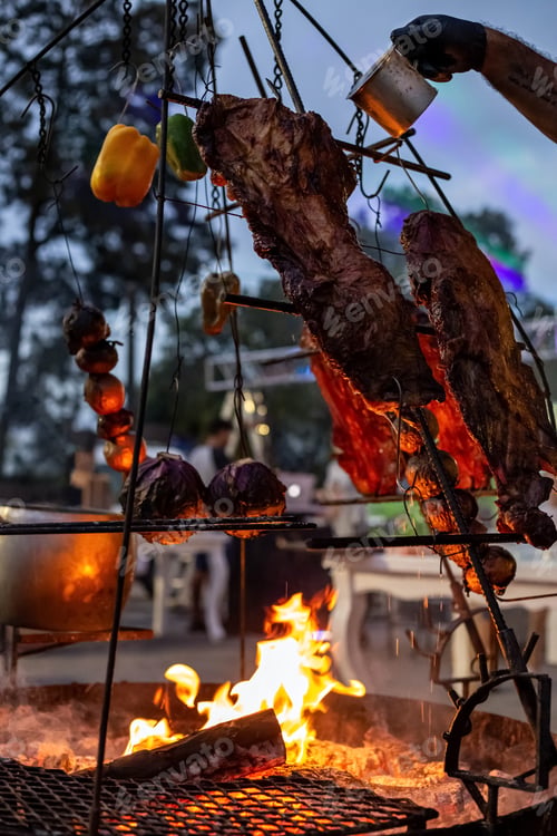 Preview: Grill loaded with roasted meat and vegetables over the fire.