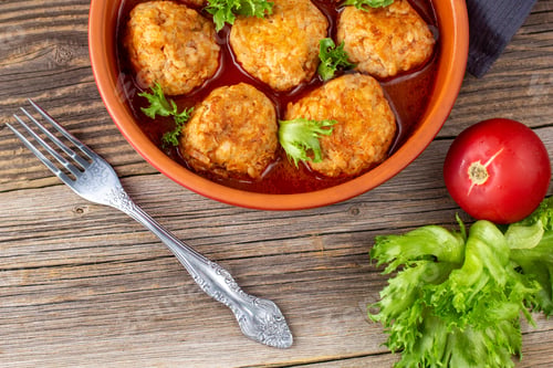 Preview: Meatballs in tomato sauce in a bowl on wooden table.